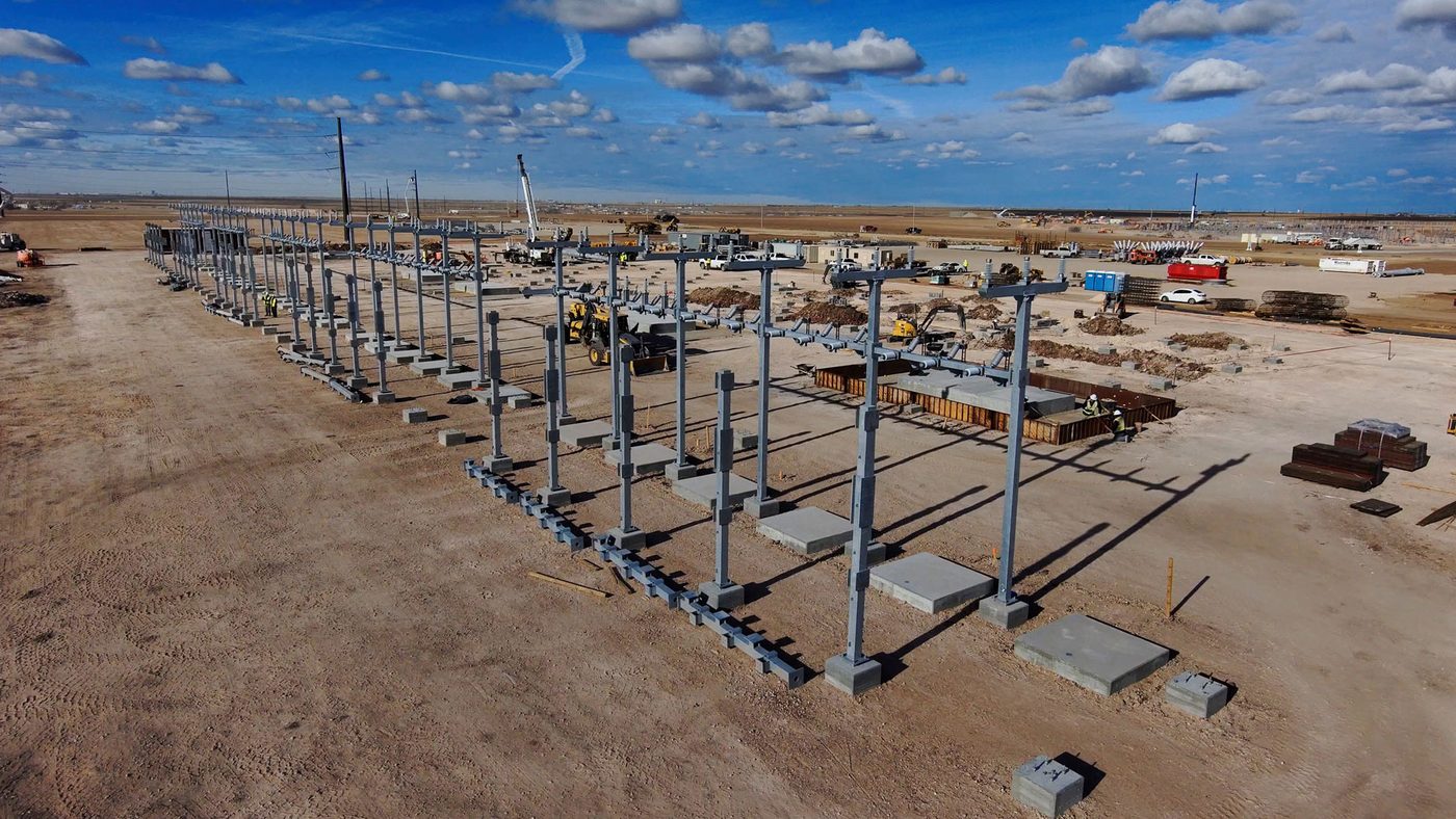 Aerial photograph of steel columns rising from concrete foundations at the Project Matador substation under a wide Texas sky